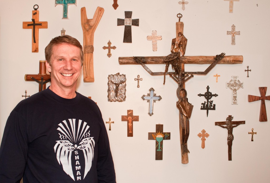 Dr. Chuck Dietzen in his home on Main Street with his collection of crosses from all over the world, including 2 from the Pope. 