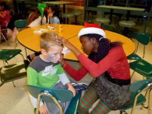 Oak Trace Elementary kindergarten Student Johnny Ewing has his face painted by Westfield High School Executive Committee member Tolu Odimayomi. The executive committee hosted the “Breakfast With Santa” on Dec. 10, 2012, which provided more than 150 elementary students with crafts, face painting, food and the opportunity to meet with Santa and Mrs. Claus. (Photo provided)
