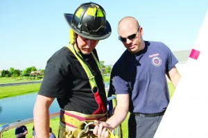 Firefighter Josh Southerland tethers a safety line to Steve Ward before his 123-foot ladder climb.