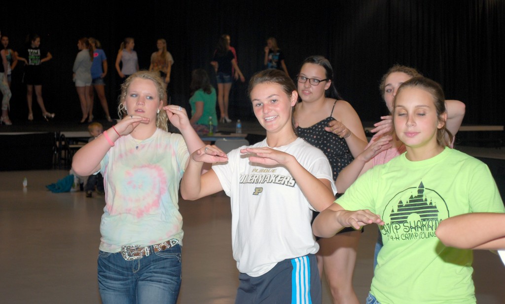 From left: Rachel Flanders, Madison McFadden, Kara Moody, Zoe Schwab and Victoria Comin rehearse the 4-H Queen Pageant opening dance routine as other contestants work on the modeling portion of the show. (Photo by Robert Herrington)