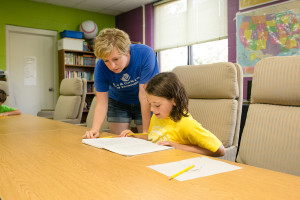 Staff member Kylie George helps member Tess Hawkins-Wilding with homework. (Photo by Anya Albonetti)