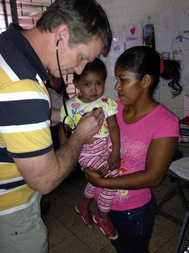 Dr. Chuck Dietzen helps a young girl in El Salvador. (photo by Jeff Cardwell with People Helping People Network)