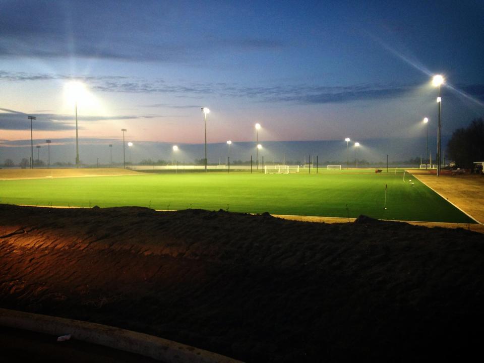 Lights shine on an artificial field as the sun rises above Grand Park. (Submitted photo)