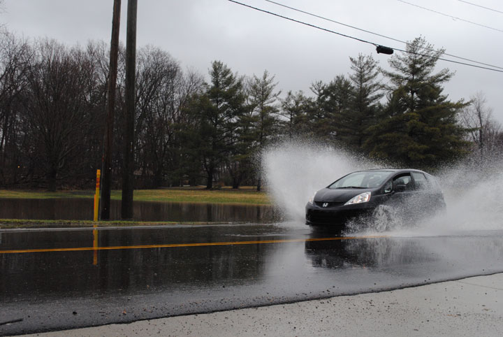 Cars drive through a flooded roadway at 126th Street in Carmel. (Staff photo)