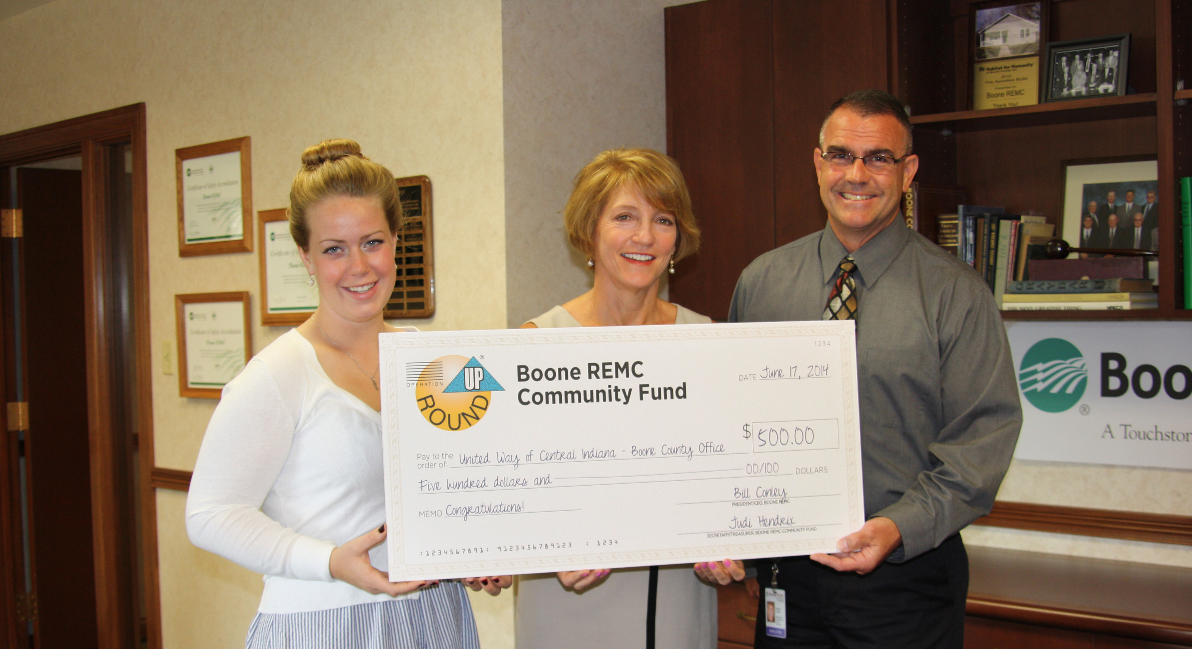 United Way of Central Indiana Boone Co. office intern Sarah Kissel and director Christie Snyder accept an Operation Round Up grant for $500 from Boone REMC President/CEO Bill Conley. The grant will go towards the Indy Backpack Attack. (Submitted photo)
