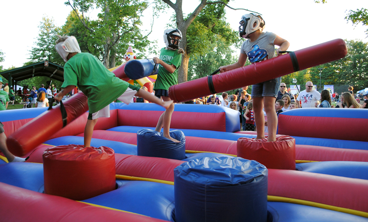 From left: Dylan Cole, Kyra Woodruff and Melody Hisey play the inflatable joust game in the kids’ area sponsored by Imagine Church. (Photo by Robert Herrington)