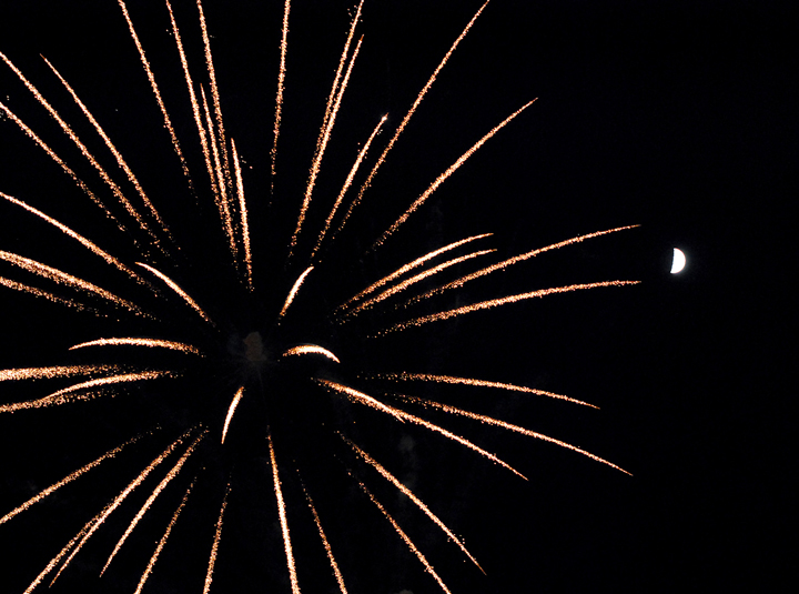Fireworks explode in the sky near a crescent moon. (Photo by Robert Herrington)