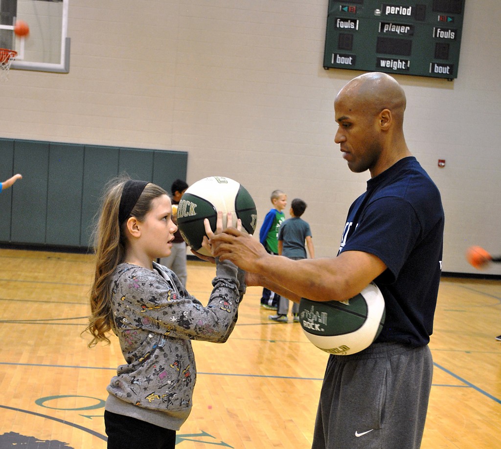 Eddie Gill helps Oak Trace Elementary student Jordyn Church properly position her hand on the basketball. (Submitted photo)