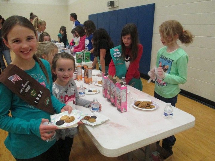 Girl Scouts Caroline and Addy Sampson sample cookies including the new Rah Rah Raisins handed out by Elise Reineking and Ashley Rogers from troop 1817. (Photo by Heather Lusk) 