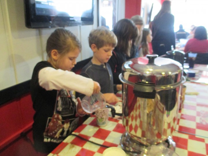 Pleasant View Elementary first-grader Vera Britenriker measures water while classmate J.D. Carpenter prepares to mix in hot chocolate. (Photo by Heather Lusk)