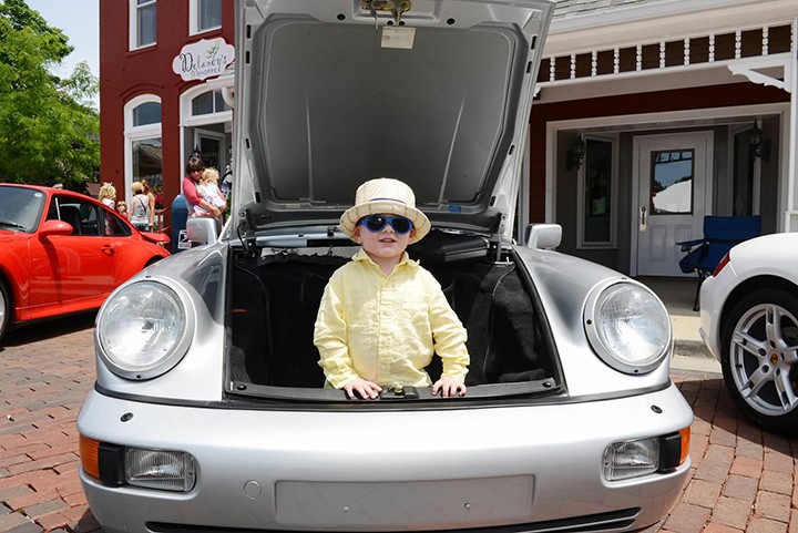 A youngster plays in the trunk of a silver Porsche. (Photo by Theresa Skutt)
