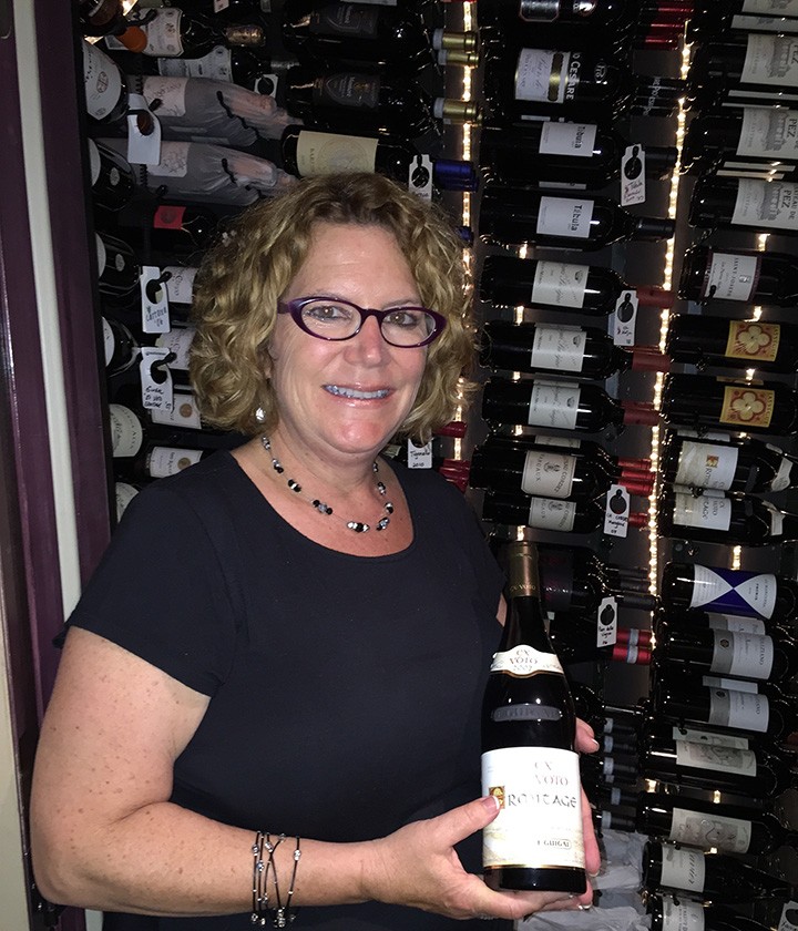 Jan Bugher holds a bottle of wine from Peterson’s. (Photo by James Feichtner)