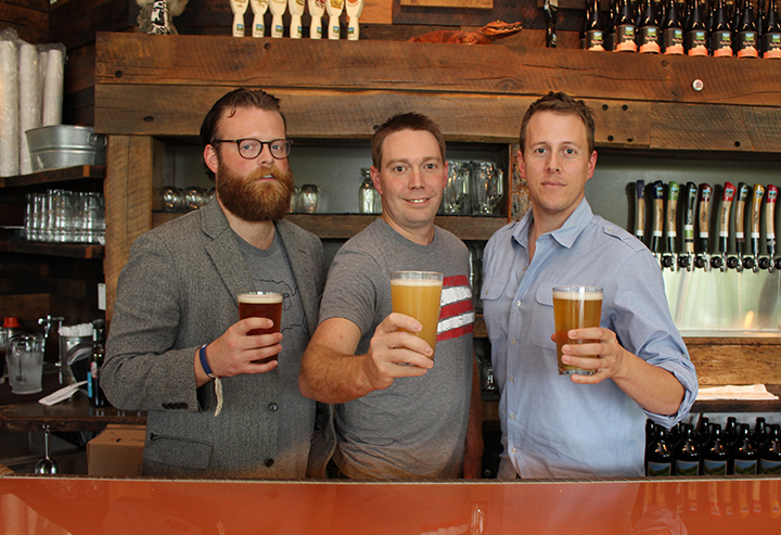 Indiana On Tap staff members Adam Schick, from left, Joel Bozman and Justin Knepp raise a glass at Upland Taproom in Carmel. (Photo by James Feichtner)