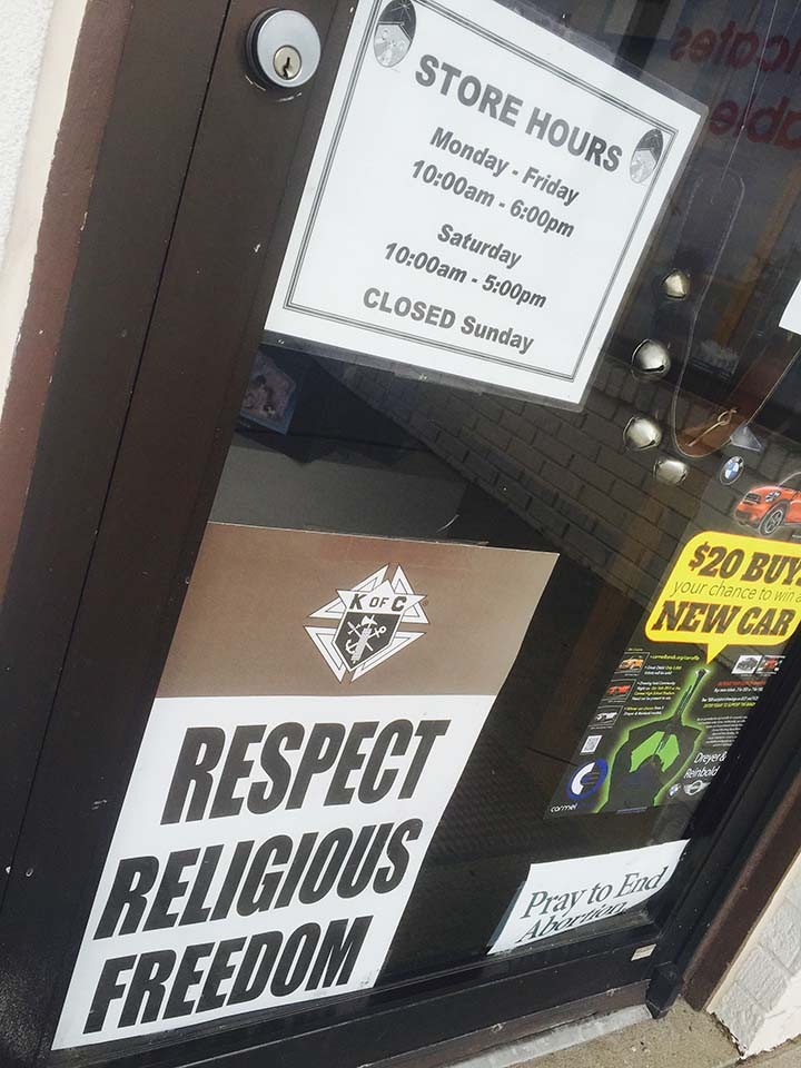 A sign on the door of Holy Family Books and Gifts reads, “Respect religious freedom.” (Photo by Adam Aasen)