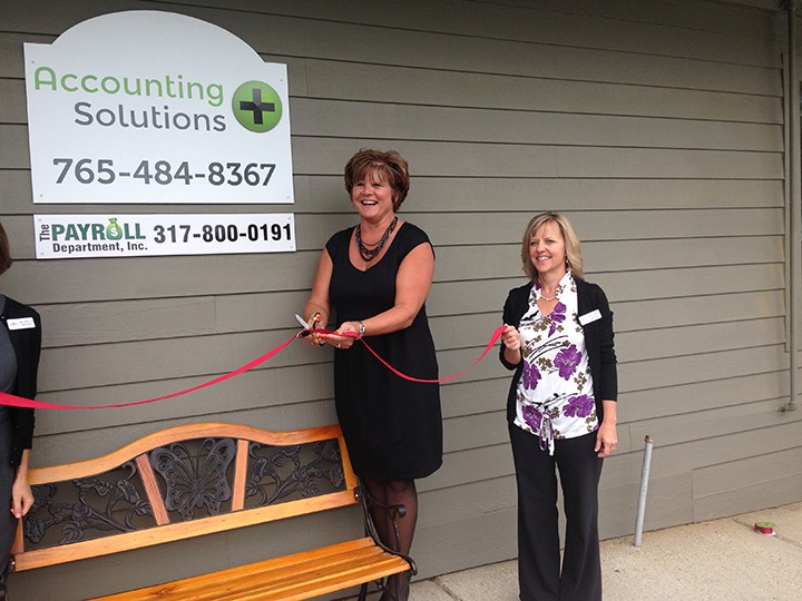 Teresa Ray, left, cuts the ribbon at the grand opening of her business with the help of Diane Schultz, Zionsville Chamber of Commerce director of member services. (Photo by Mark Ambrogi)