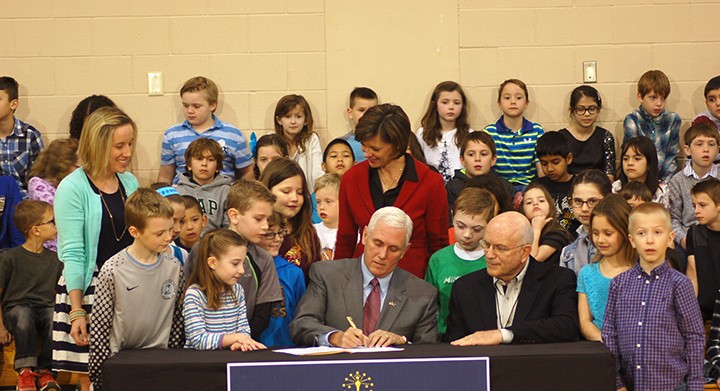 Pence signs the bill to end ISTEP testing surrounded by Eagle Elementary students and staff. (Photo by Heather Lusk)