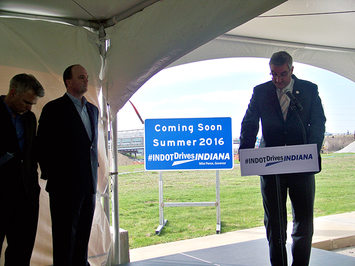 From left, INDOT Deputy Commissioner Ryan Gallagher and Fishers Mayor Scott Fadness stand by as Lieutenant Gov. Eric Holcomb speaks with the Ind. 69 and 106th Street interchange in the background April 6 in Fishers. (Photo by Sam Elliott)