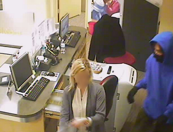 The individual wearing the blue hooded sweatshirt is one of two suspects connected to three robberies at the Kemba Credit Union at 5625 Sunnyside Rd. (Submitted photo)