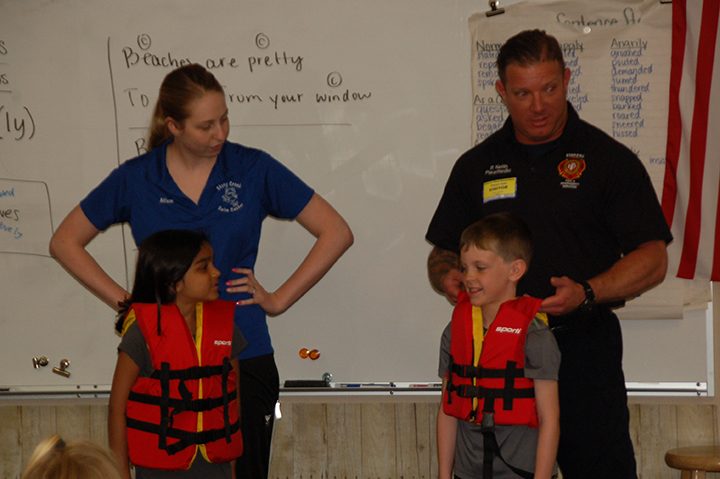 Stony Creek Swim Center Aquatics Director Allison Roberts and Fishers Firefighter Patrick Keith show students the proper technique for checking the correct fit of a life jacket during a recent water safety presentation at Hoosier Road Elementary. (Submitted photo)