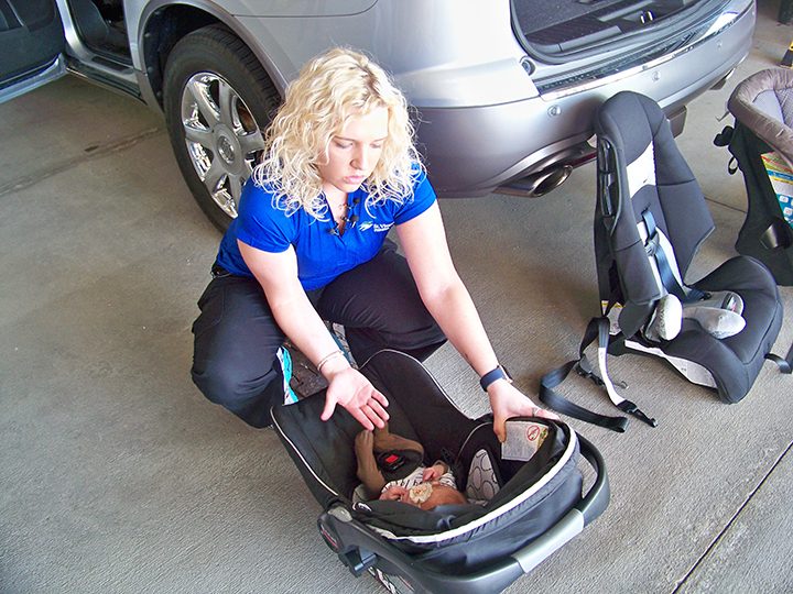 St.Vincent Fishers’ certified car seat technician Amanda Craft demonstrates proper methods for strapping baby volunteer Kooper Noone into her car seat before showing how to properly install the seat into a vehicle. (Photo by Sam Elliott)
