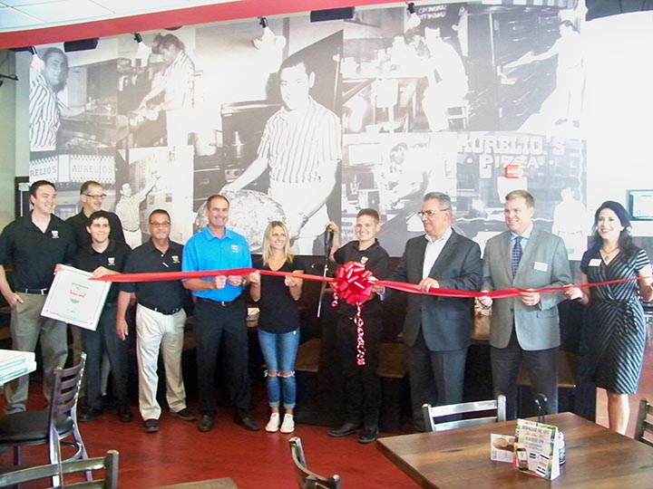 Local and corporate Aurelio’s staff members are joined by Fishers City Council members to celebrate the grand opening of the new Fishers restaurant. On the wall are photos from the original Aurelio’s founded in 1959 in Homewood, Ill. (Photo by Sam Elliott)