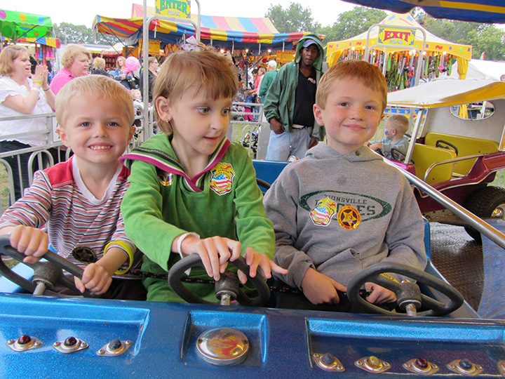 Shea Weidner, center, takes her first carnival ride at a previous VIP Carnival, with her brothers, Cruz, left, and Von by her side. (Submitted photo)