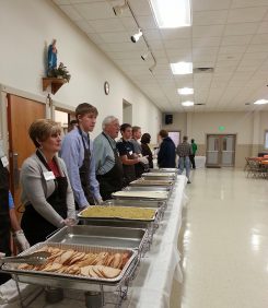 Volunteers at St. Louis de Montfort Catholic Church dish out food during last year’s Thanksgiving dinner. (Submitted photo)