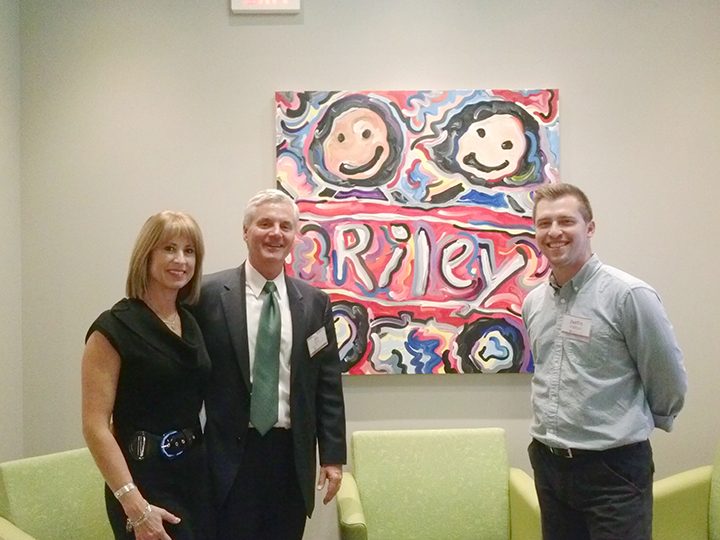 From right, Justin Patten pauses with Riley Children’s Hospital Chief Marketing and Corporate Partnership Officer Jim Austin and Barb Austin near a painting Patten created that hangs in Riley’s corporate downtown office. One of the 2016 Riley Hospital for Children ornaments features artwork by Justin Patten. Proceeds benefit the hospital. It is available at rileyholidaycards.com.
