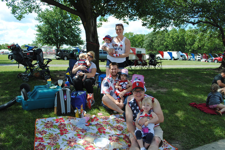 From left, Christina Gibson, Redford Gibson, Elliot Simpson, Meredith Simpson, James Simpson, Norah Simpson, Ryan Gibson and Lilah Gibson find a shady spot to watch the parade. (Photo by Anna Skinner)